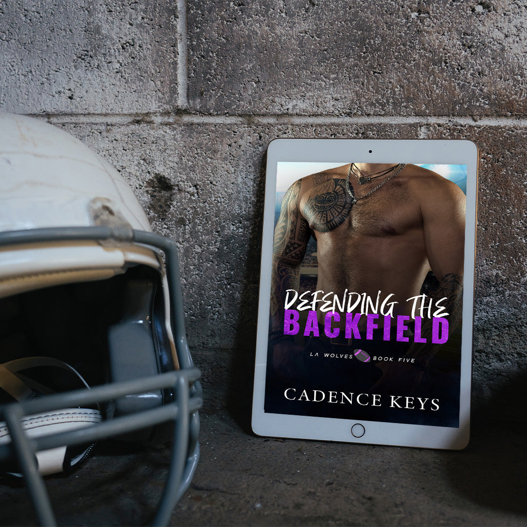ebook of Defending the Backfield by Cadence Keys against a cement wall and next to a football helmet.